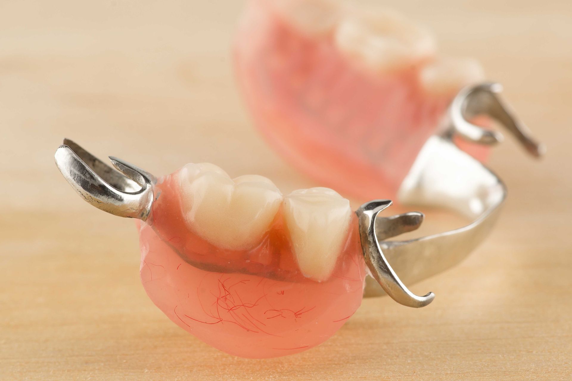 Due protesi parziali rosa con ganci metallici su una superficie chiara
