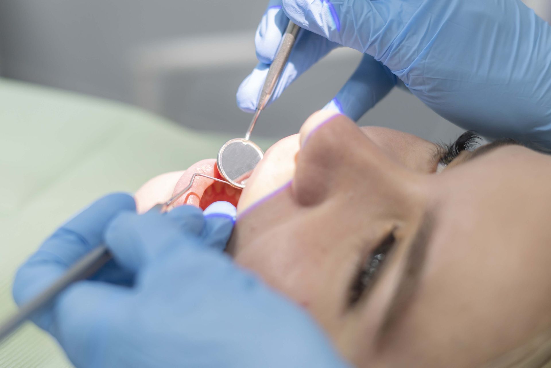 Un dentista utilizza uno specchietto dentale per esaminare i denti di un paziente in clinica.