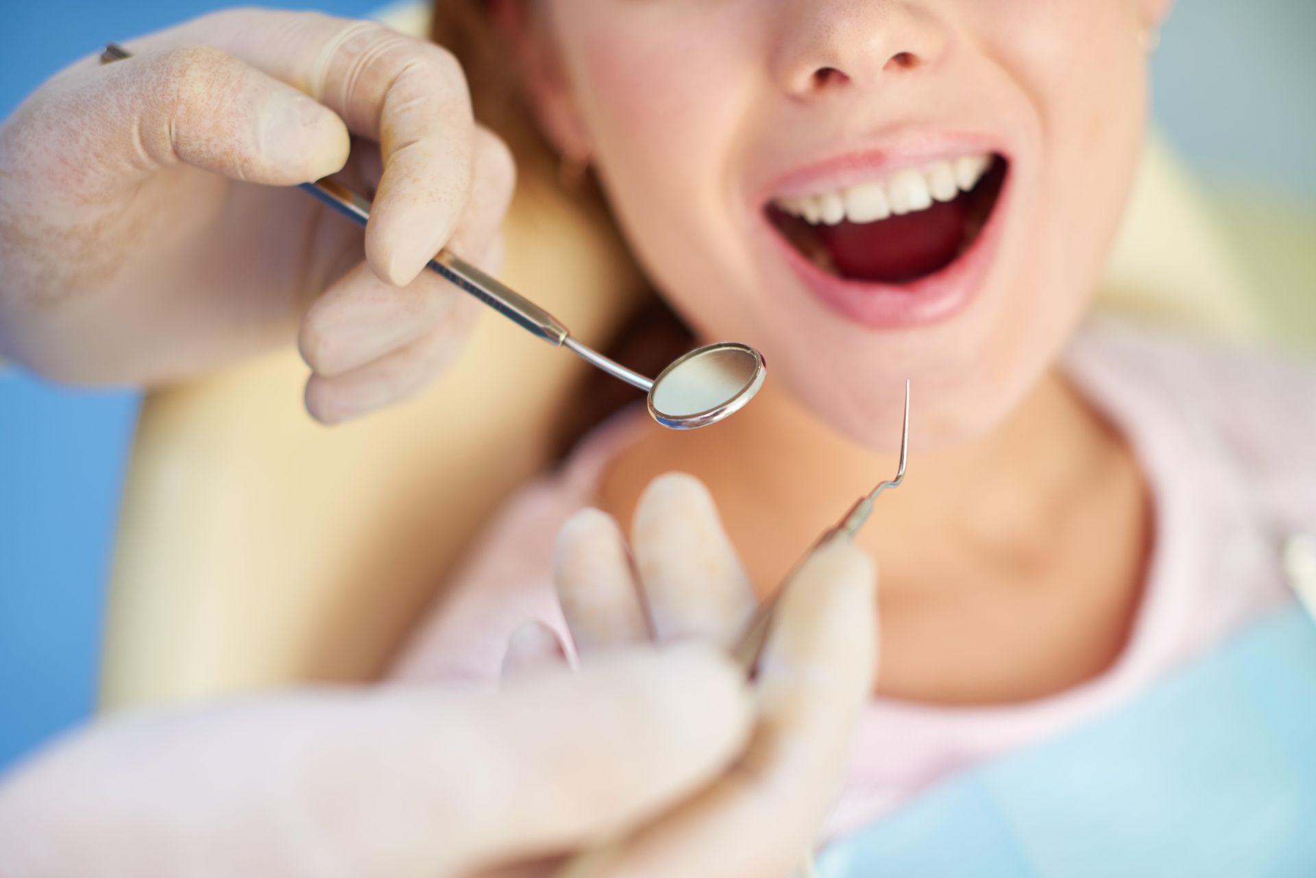 Il dentista utilizza uno specchio e una sonda all'interno della bocca aperta del paziente durante una visita.
