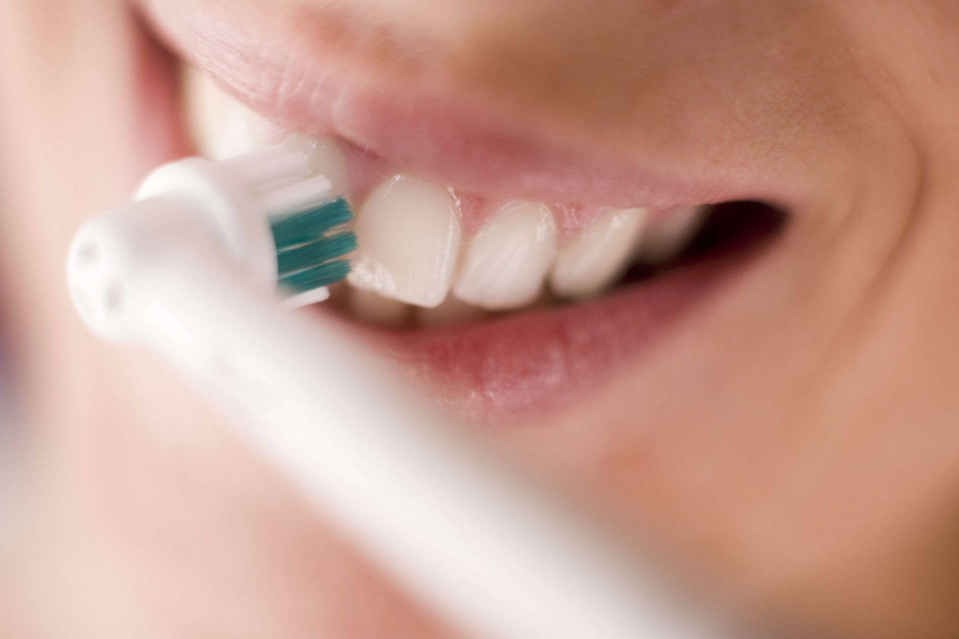 Una persona si lava i denti con lo spazzolino vicino a una bocca sorridente