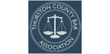 Thurston County Bar Association seal with white scales of justice on a dark blue circular emblem