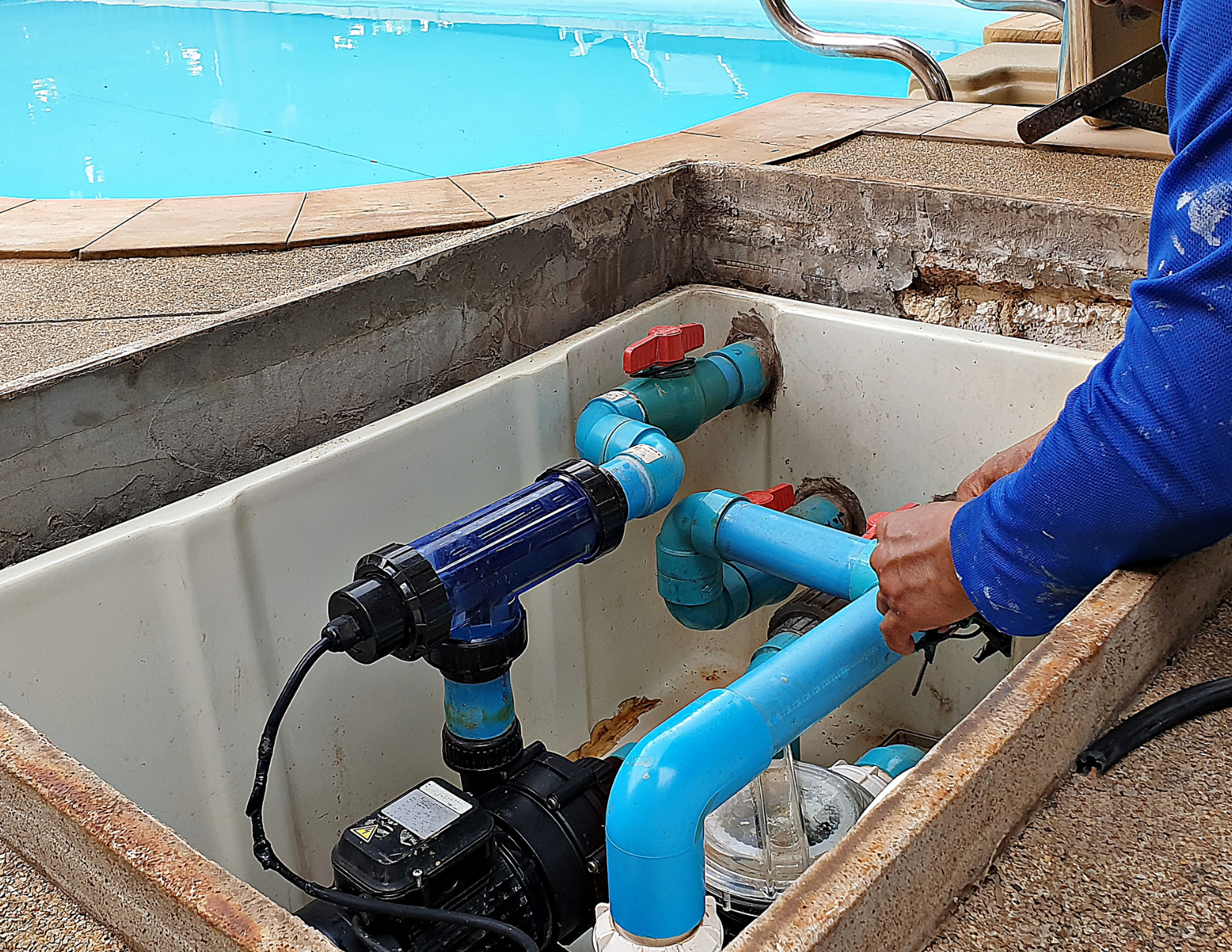 A man is working on a swimming pool pump.