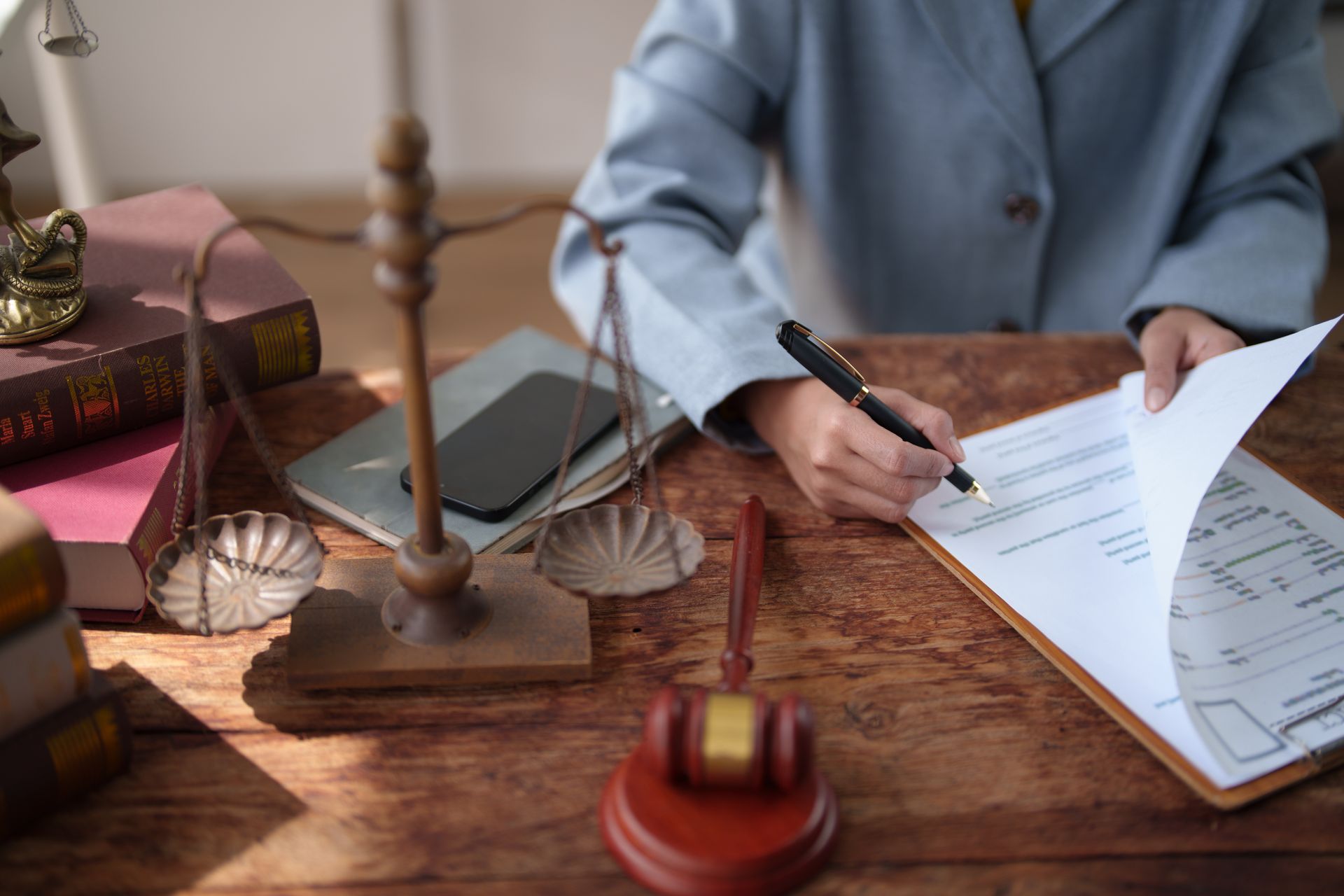 Criminal defense lawyer concept with gavel and handcuffs on desk. Lawyer's hands signing a contract or important document.