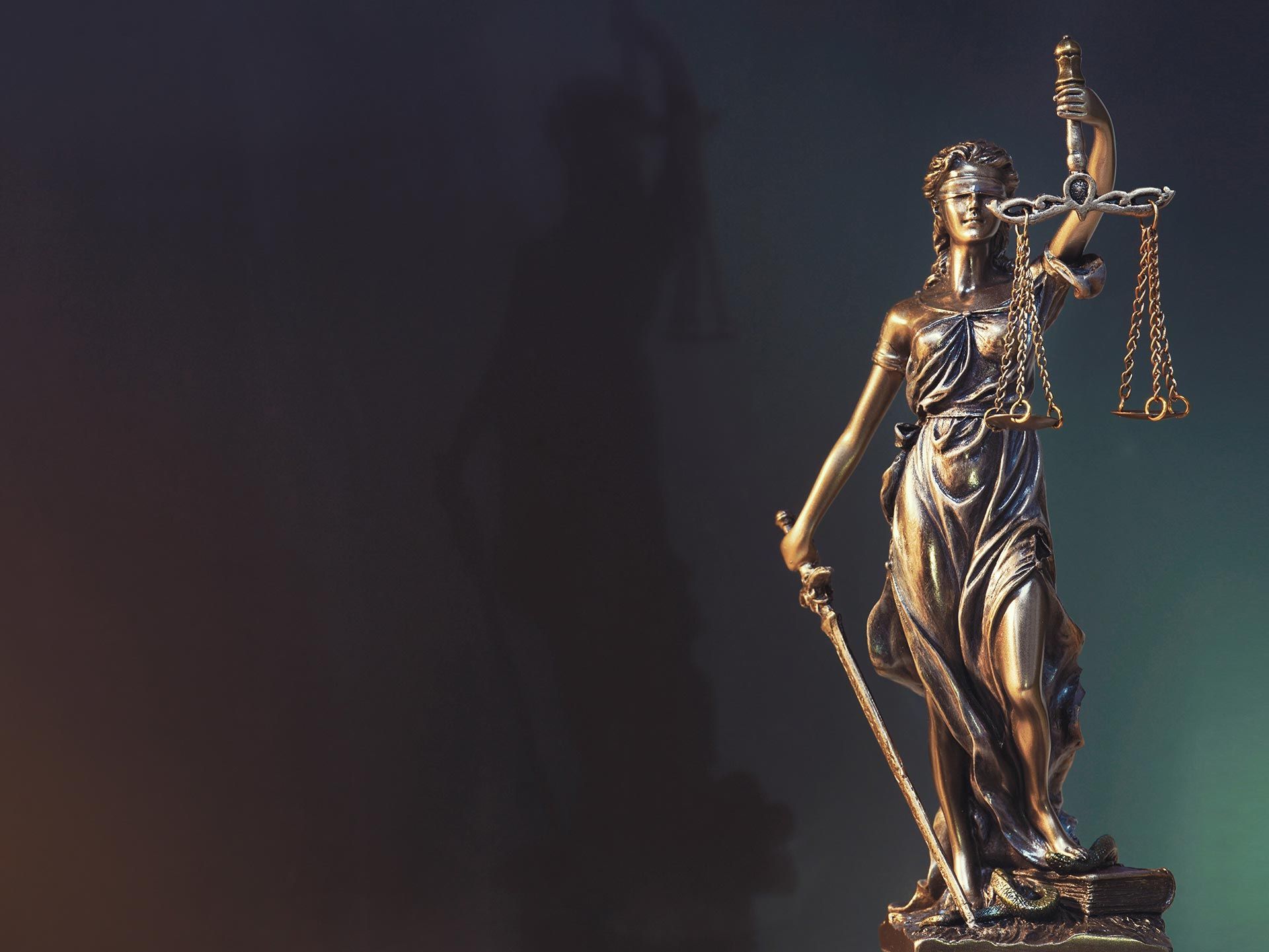 Statue of Lady Justice holding scales and sword, set against a dark background. Statue of Lady Justice holding scales and sword, set against a dark background.