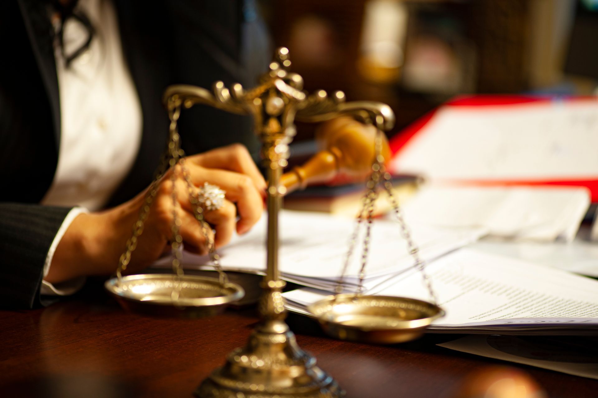 Close-up of justice scales and gavel on desk with legal documents.