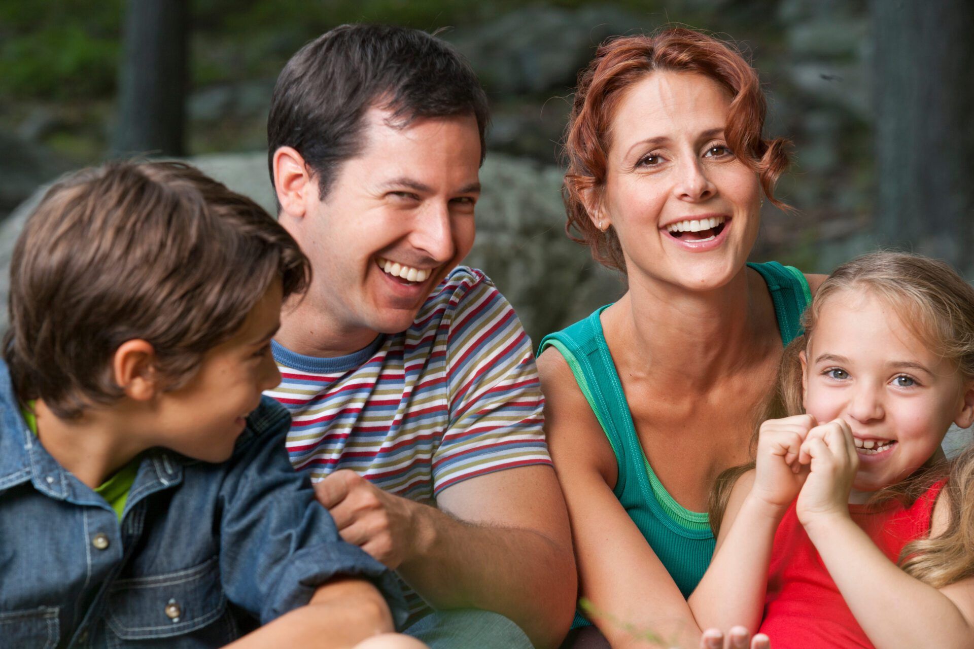 a family is sitting on a couch and laughing together .