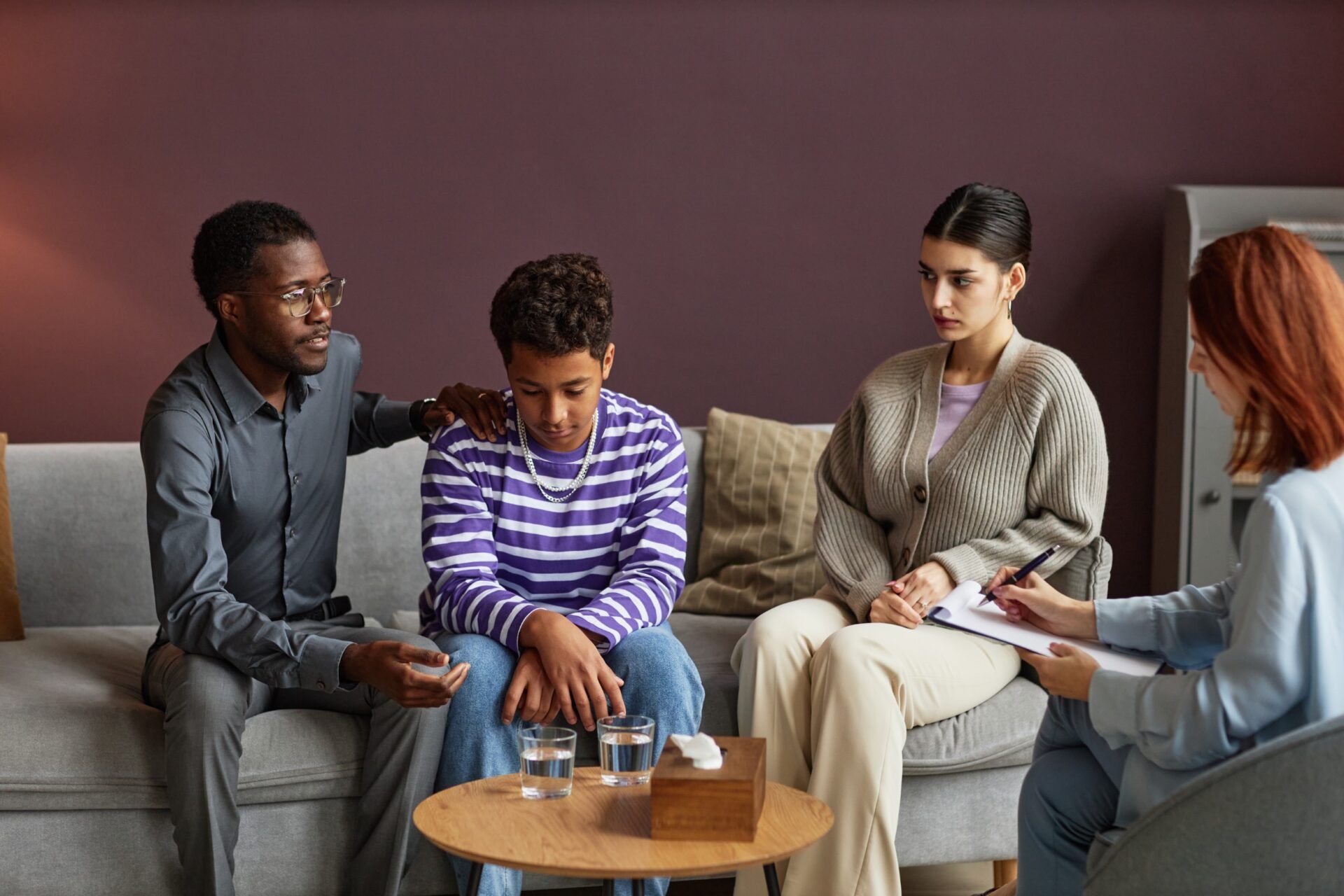 a group of people are sitting on a couch talking to a therapist .