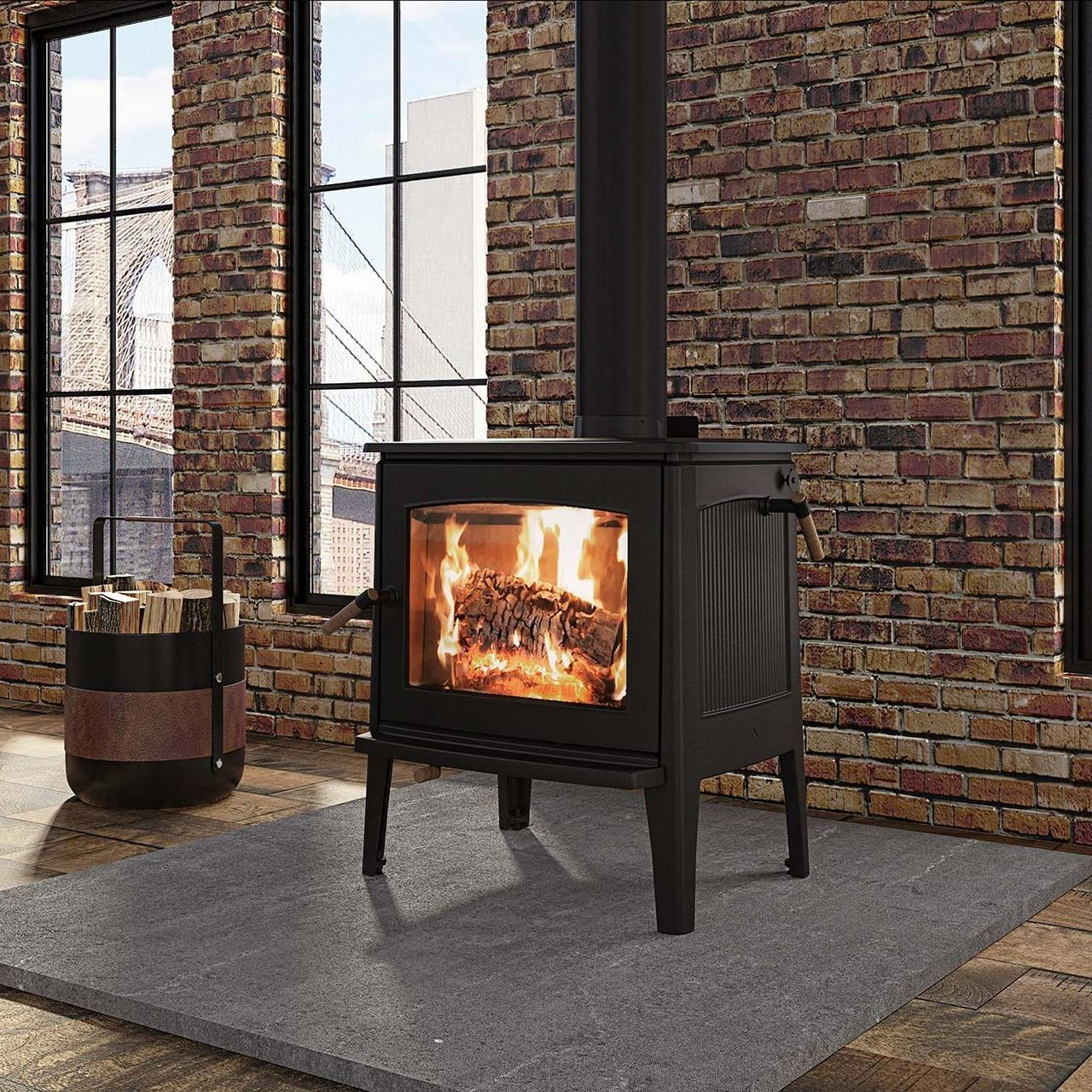 A black wood-burning stove with a roaring fire is set on a gray rug in front of a brick wall.  A barrel of wood sits to the left.