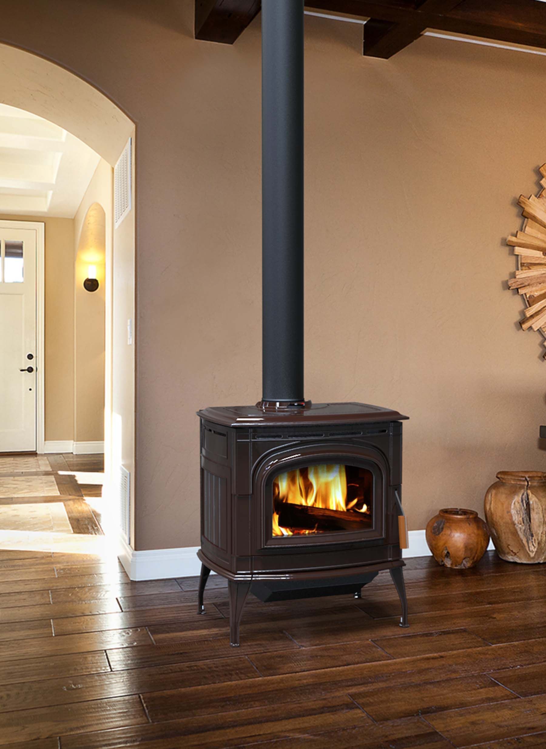 A cast iron wood-burning stove with a black pipe in a living room with wooden floors. The stove has flames visible inside.