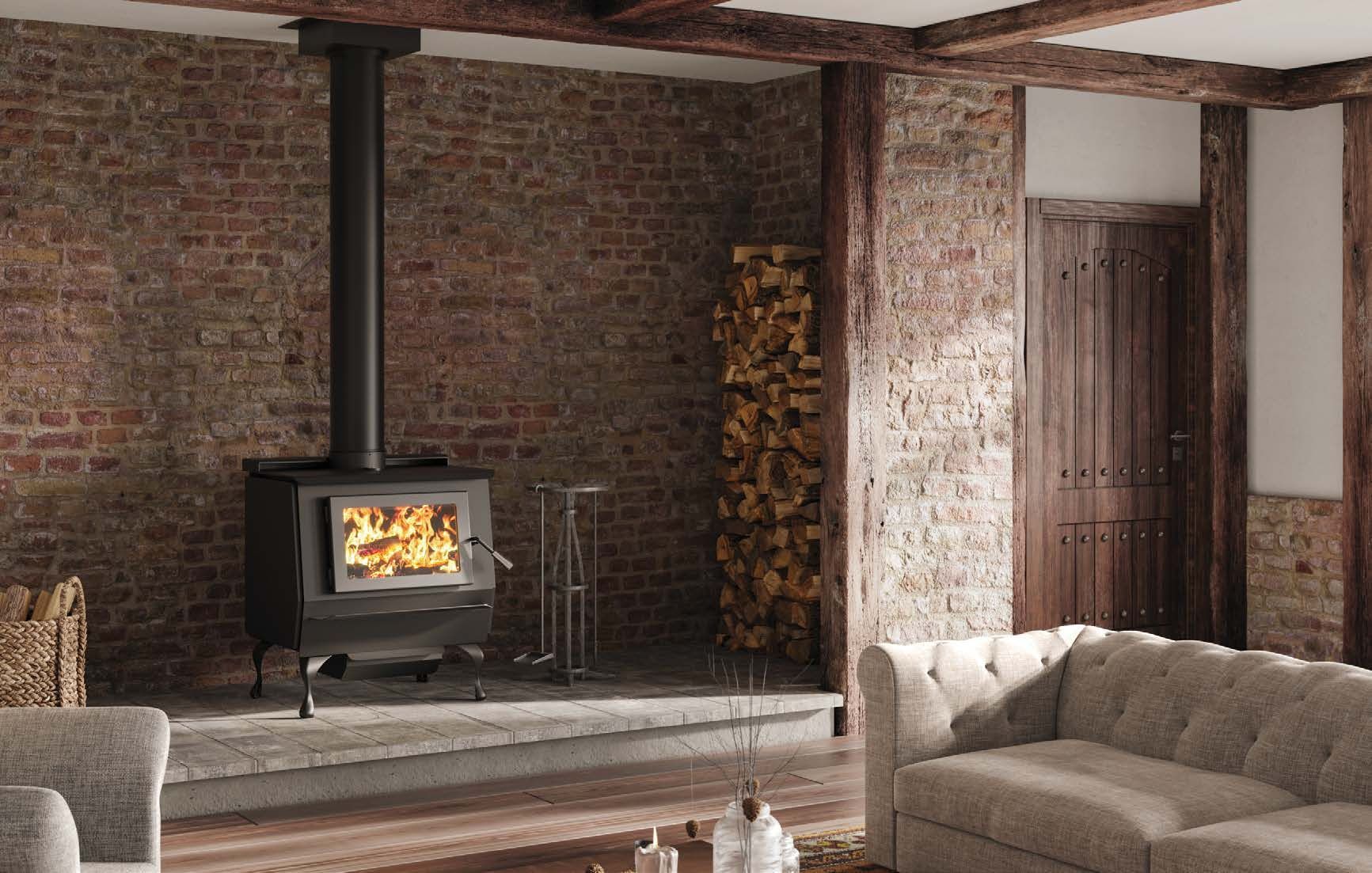 Cozy living room with a lit wood-burning stove against a brick wall, wood storage, and a tufted couch.