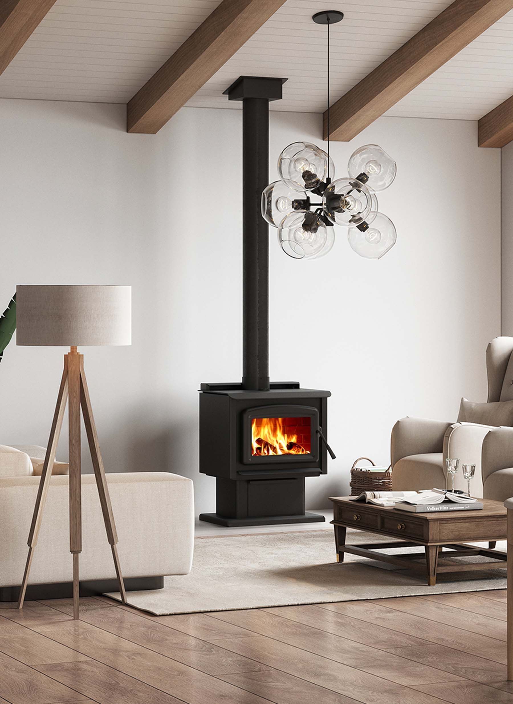 A modern living room with a black wood-burning stove.  Wooden beams, light-colored furniture, a wooden floor, and a flower-shaped chandelier.
