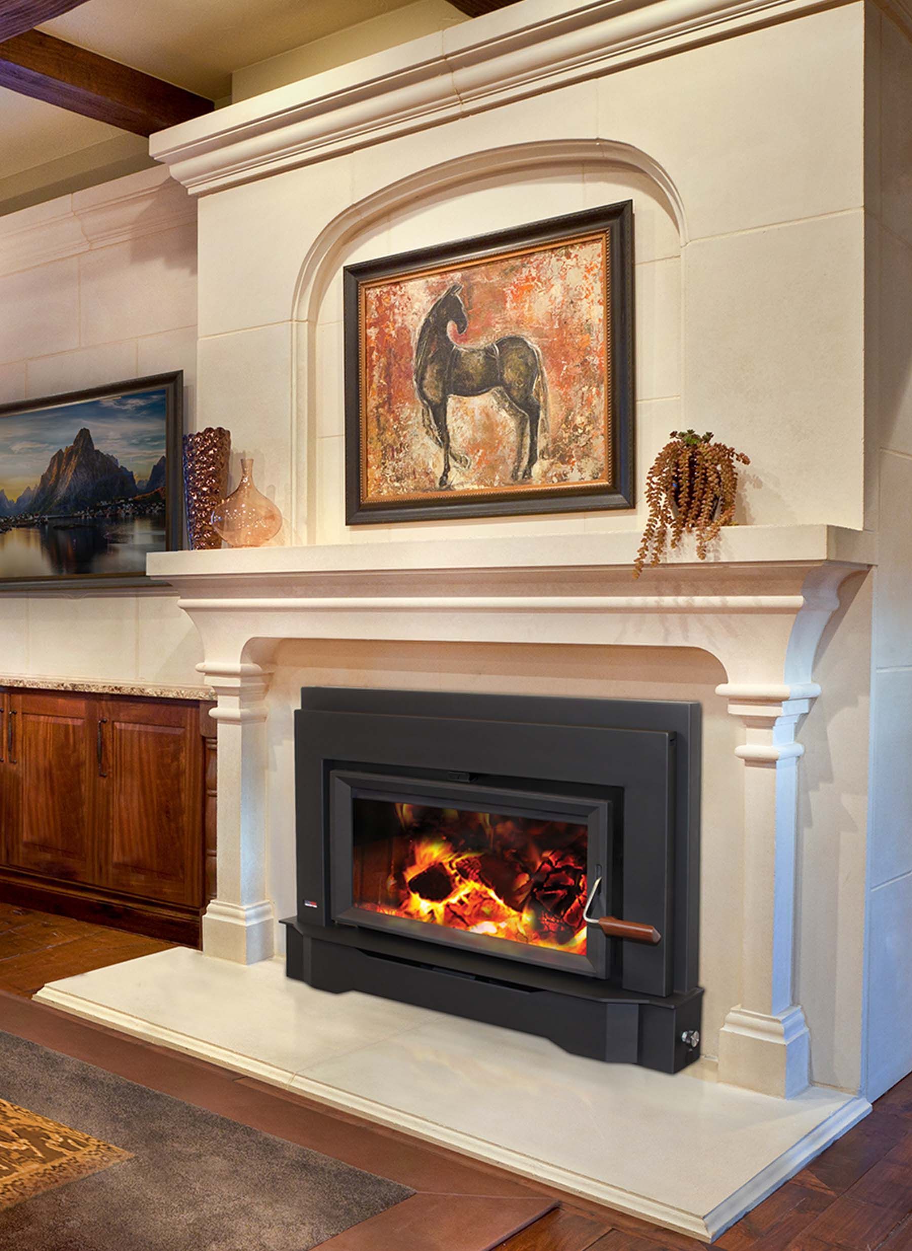 Fireplace with a black insert, surrounded by a cream-colored mantel. Artwork and decorative items adorn the mantel.