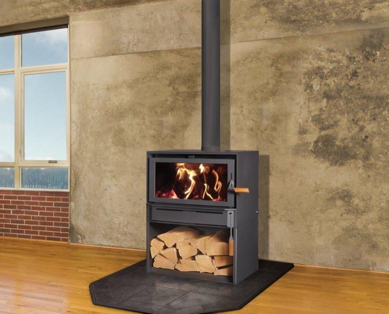 Wood-burning stove in a modern room with firewood storage below. Flames are visible in the firebox.