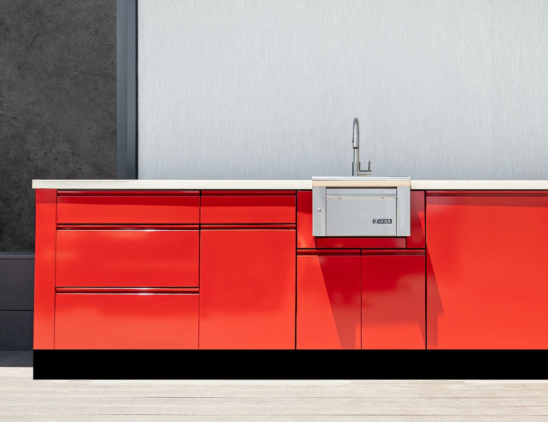 Red modern kitchen cabinets with a built-in sink and dishwasher, against a white and grey wall.