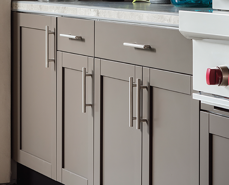 Gray kitchen cabinets with silver bar handles; partially visible oven to the right.