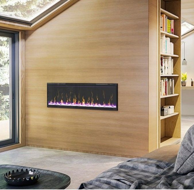 Electric fireplace mounted on a wood-paneled wall with a bookshelf. The fireplace shows colorful flames, inside a modern living space.