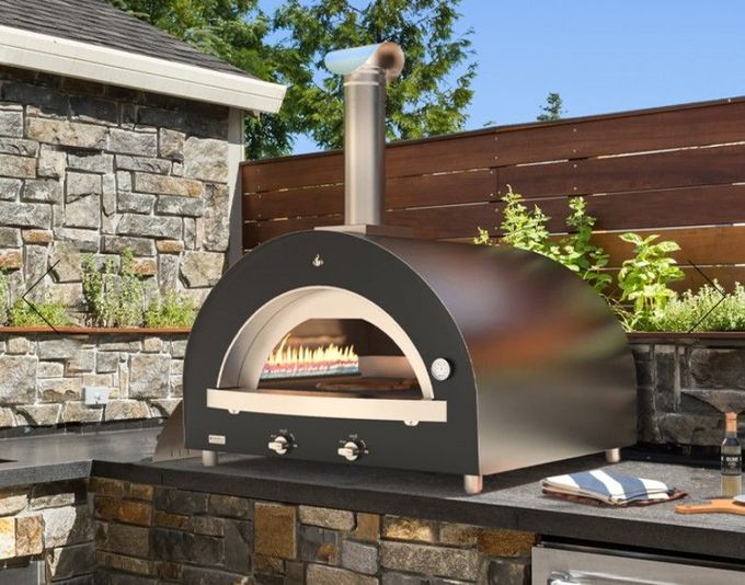 A pizza is being cooked in an outdoor pizza oven.