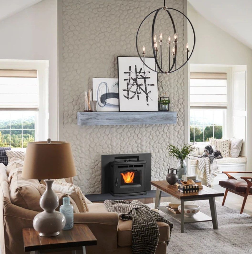 Cozy living room with a fireplace, artwork, and a chandelier. Neutral tones and natural light create a comfortable ambiance.