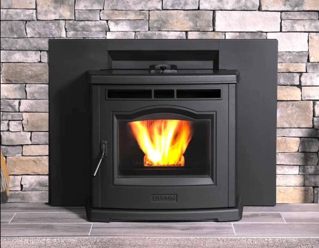 Black pellet stove with flames in a stone fireplace setting.