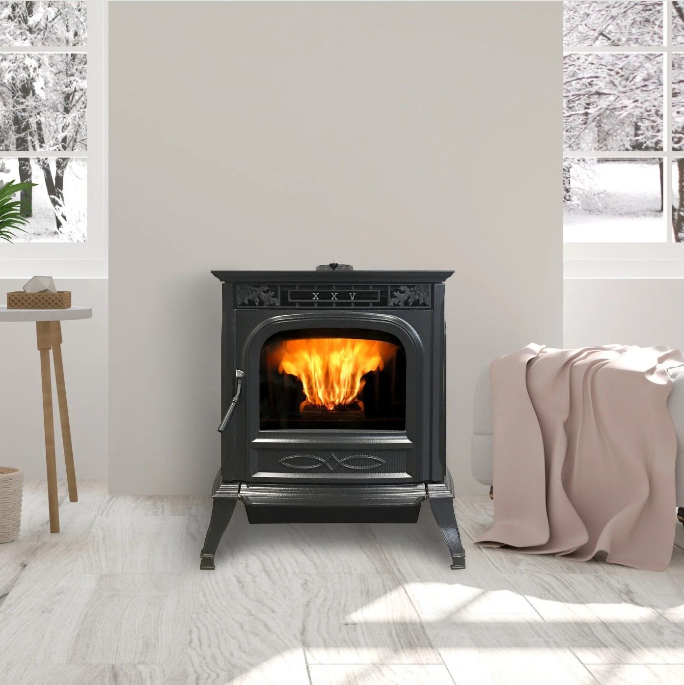 A black cast iron stove with a burning fire sits in a room with snowy views outside the windows. A blanket rests on a nearby bed.