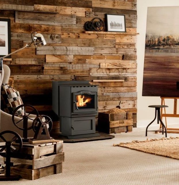 A rustic living room with a wood-paneled wall, a fireplace, art easel, and industrial decor.