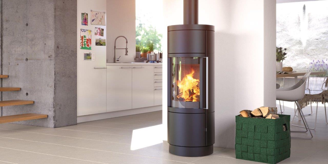 A black, modern fireplace with flames burning inside. A basket of wood sits beside it in a bright, contemporary living space.