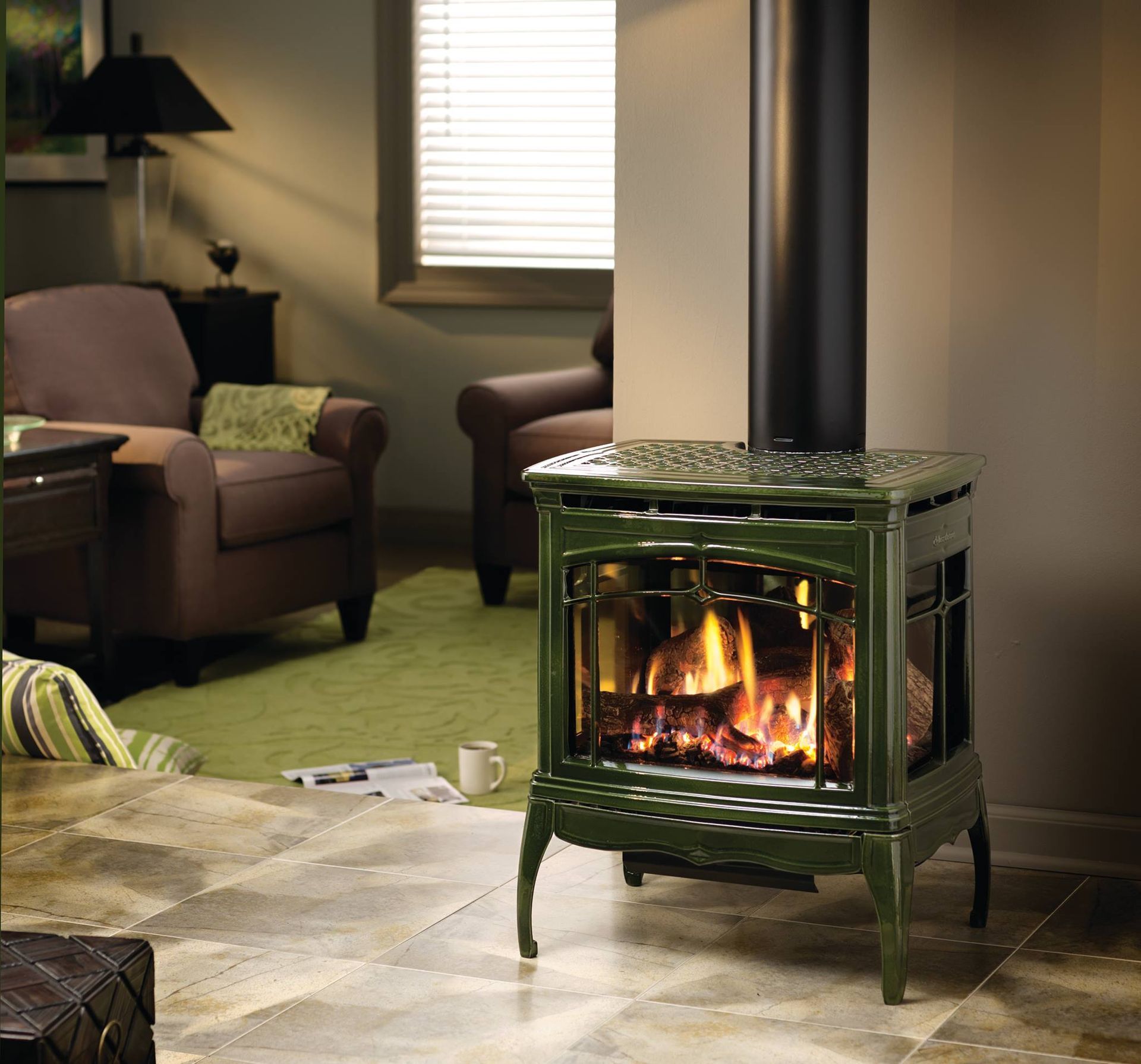 Green cast iron fireplace with lit flames, in a living room with furniture and a black chimney pipe.