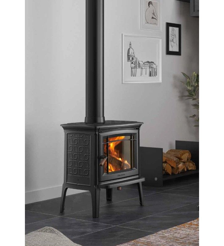 A black wood-burning stove with a lit fire, black chimney, and a stack of logs in a modern living room.