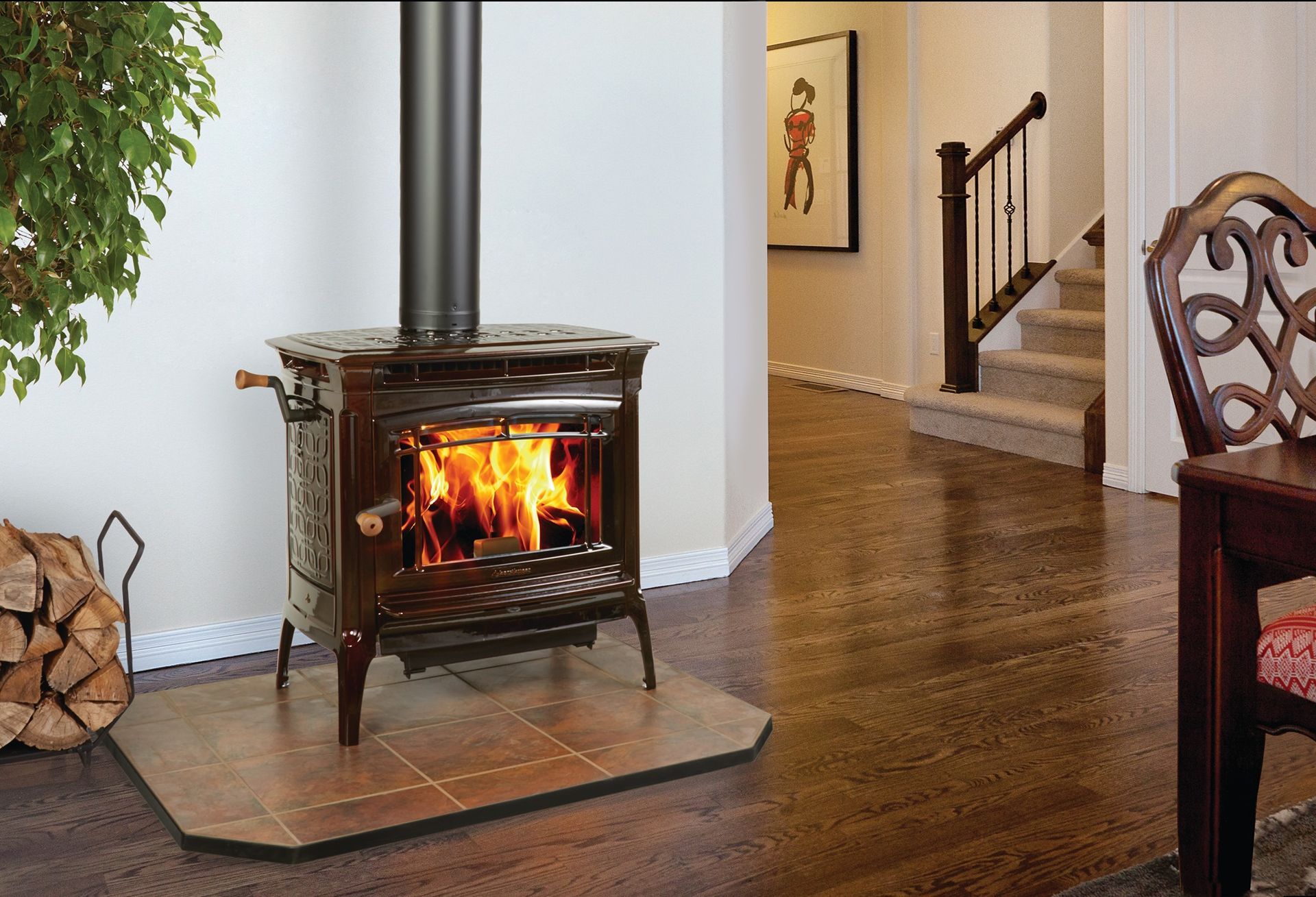 Wood-burning stove with flames in a living room, next to a stack of wood and a house plant.