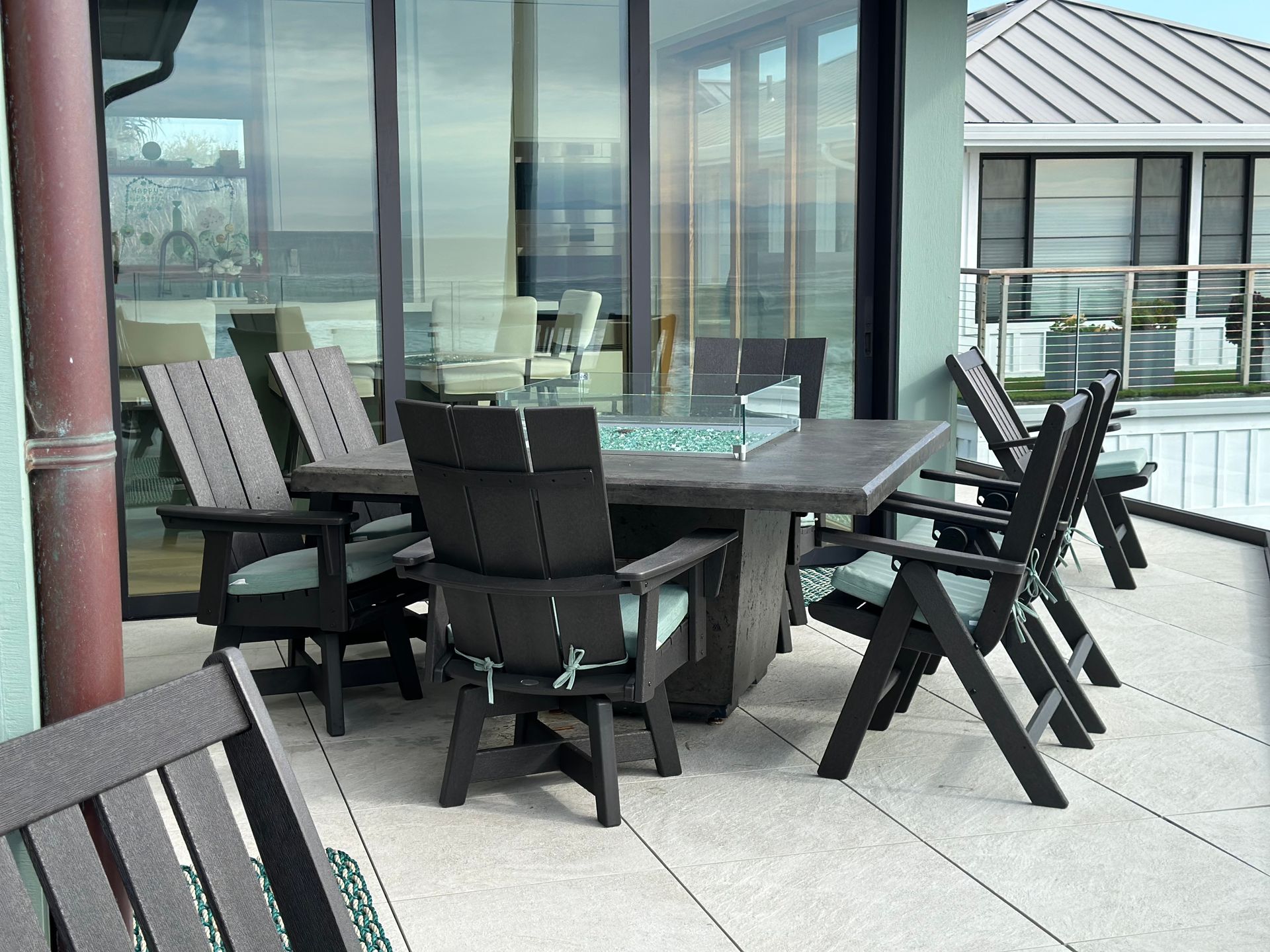 Outdoor patio with a dark wooden dining table and chairs. The chairs have light green cushions.