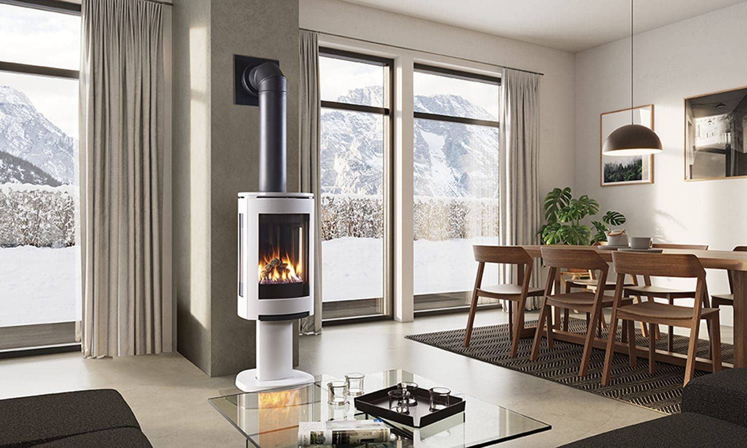 A modern white fireplace in a bright living room with large windows overlooking a snowy mountain view. A dining table with chairs is set nearby.