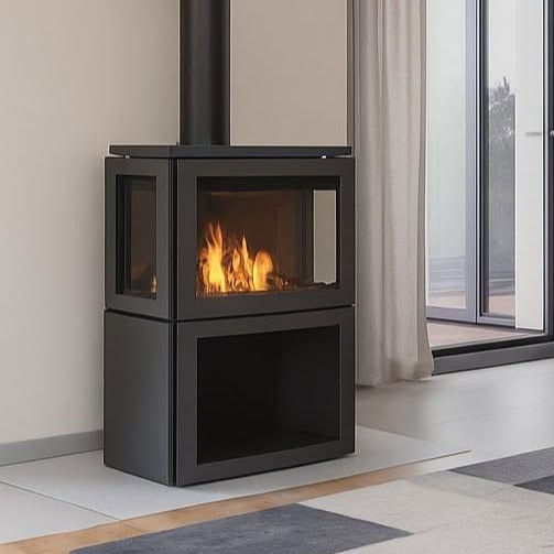 White freestanding fireplace against a brick wall, in a cozy living room with a green accent wall, armchair, and wooden floors.