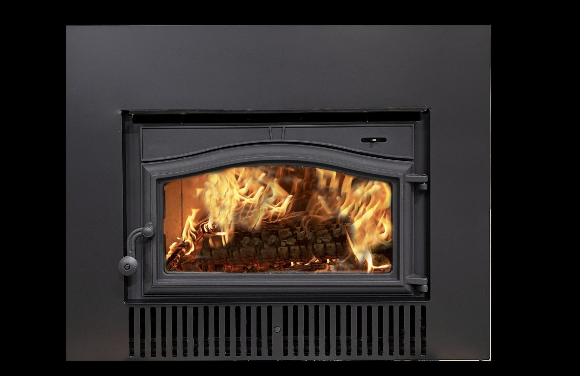 A black fireplace insert with a burning fire visible through its glass door, set against a black background.