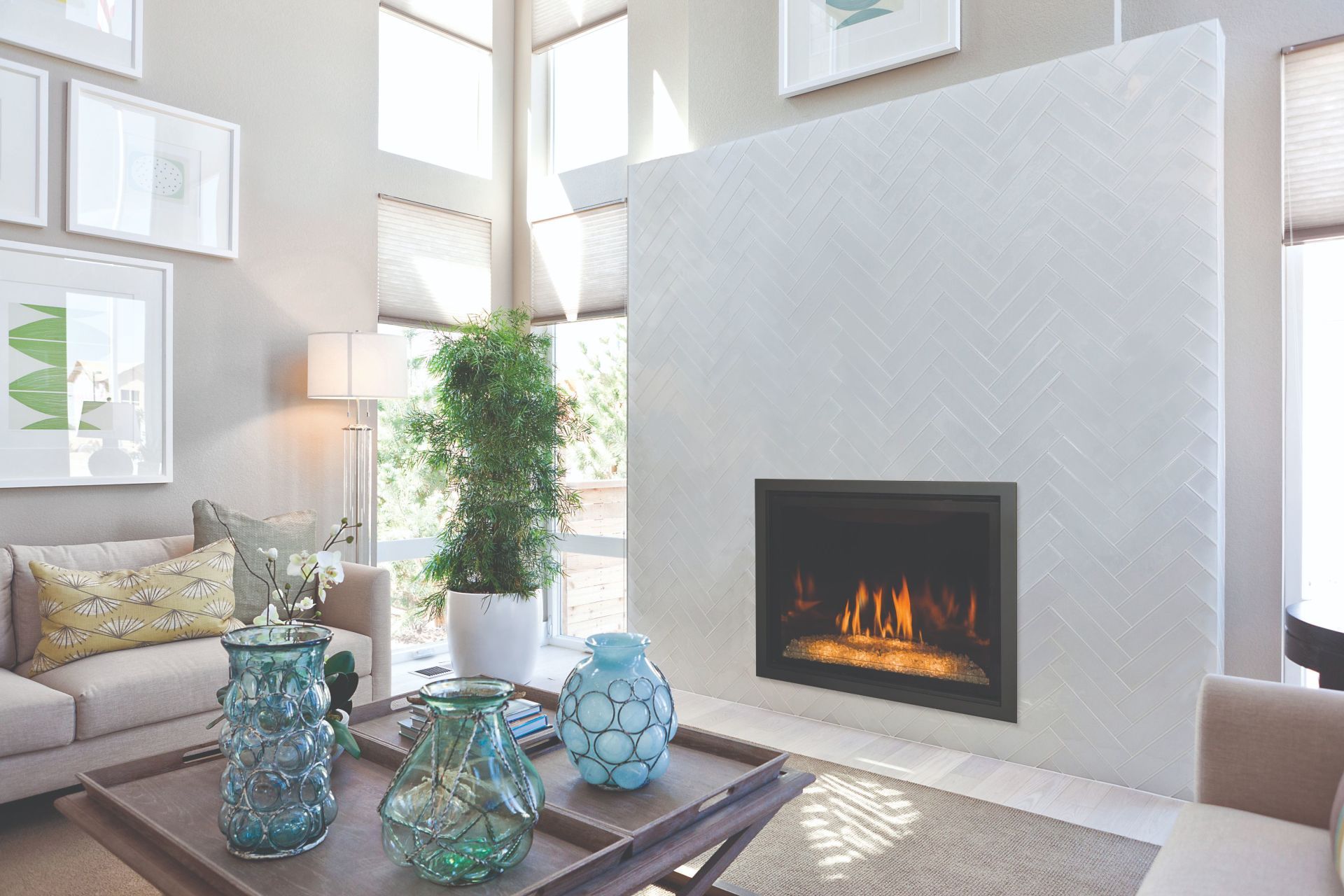 Living room with a fireplace, light walls, and decor. A sofa, coffee table with vases, and framed art complete the space.