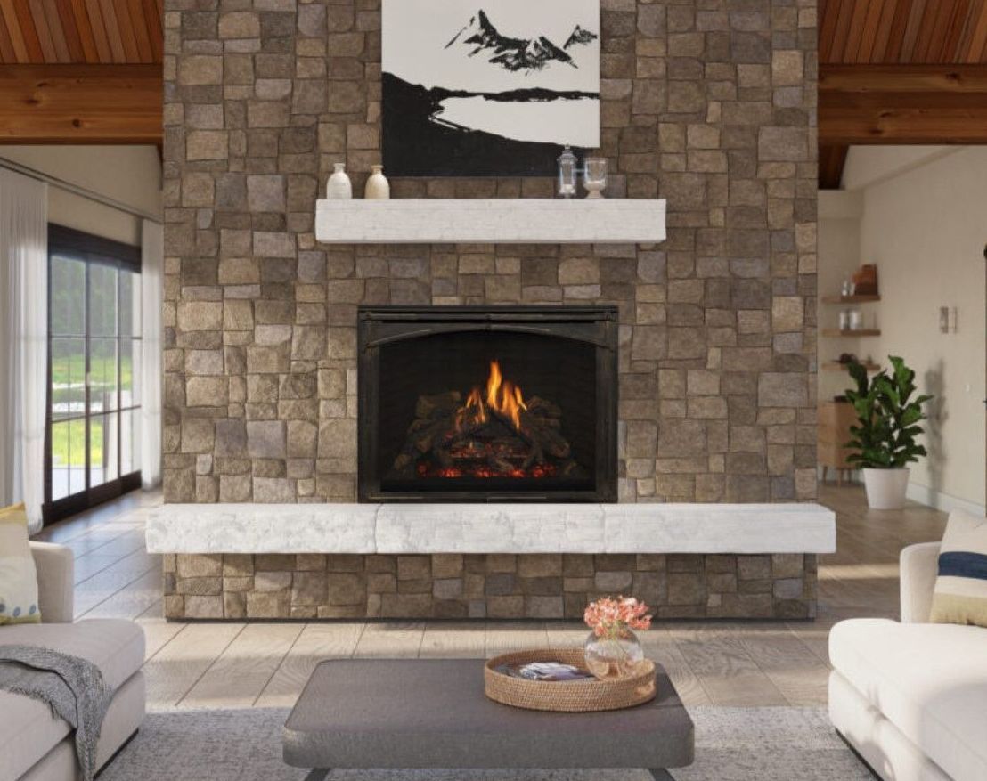 Fireplace with lit flames, set in a stone wall. A marble shelf supports art and decor; a living room setting.