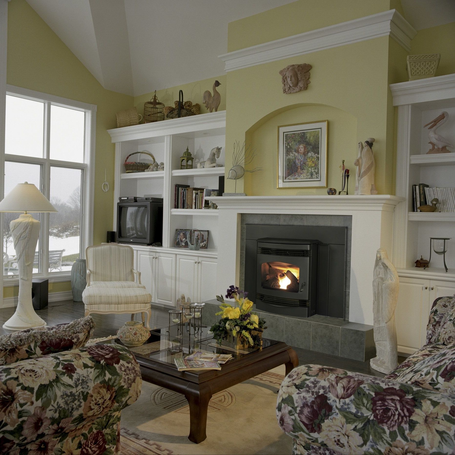 Cozy living room with a fireplace, floral patterned armchairs, and built-in bookshelves.