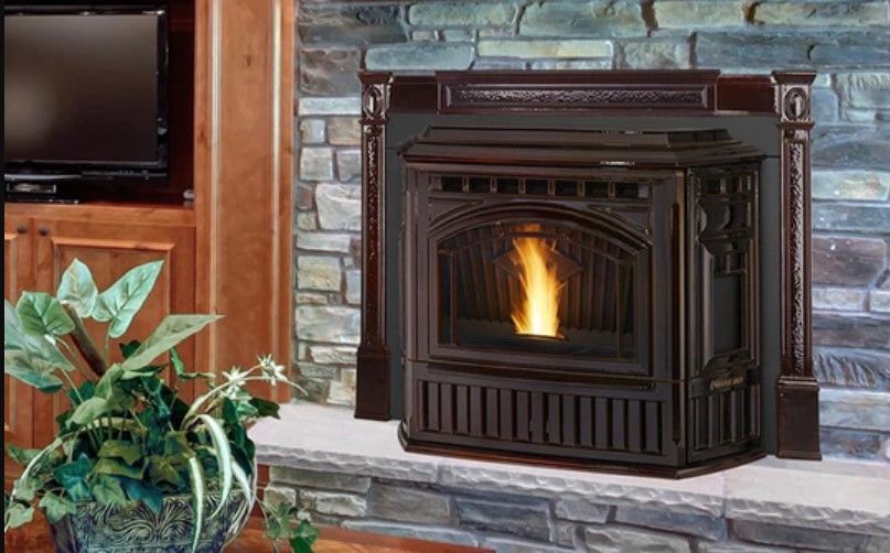 A dark brown pellet stove with a glowing fire in a stone fireplace setting. The stove is surrounded by dark brown molding.