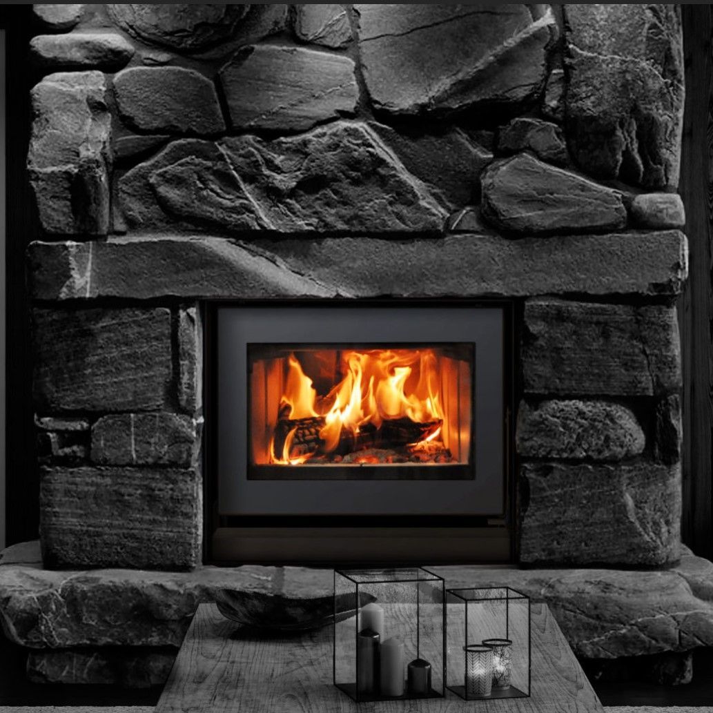 Black and white fireplace with burning fire, surrounded by a stone facade. Decorative candles sit in the foreground.