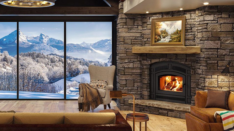 Cozy living room with a large window overlooking snow-covered mountains, fireplace, armchair, and a sofa.