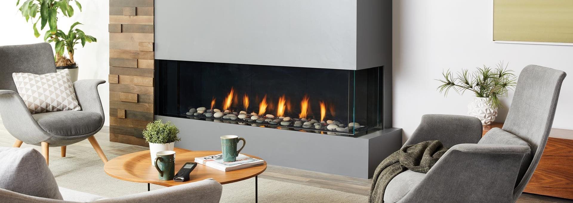 Cozy living room with a modern gray fireplace, two armchairs, and a wooden coffee table.  Flames dance within the fireplace.