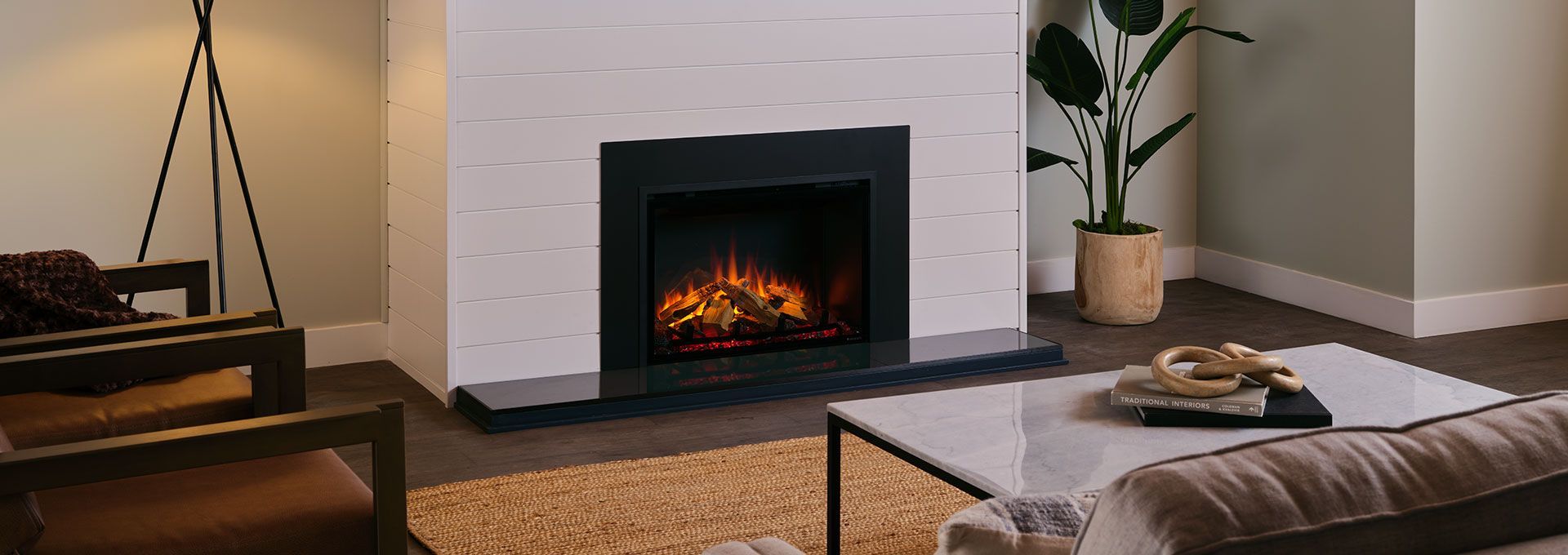 A modern living room with a lit fireplace, a sofa, a coffee table, and a potted plant.