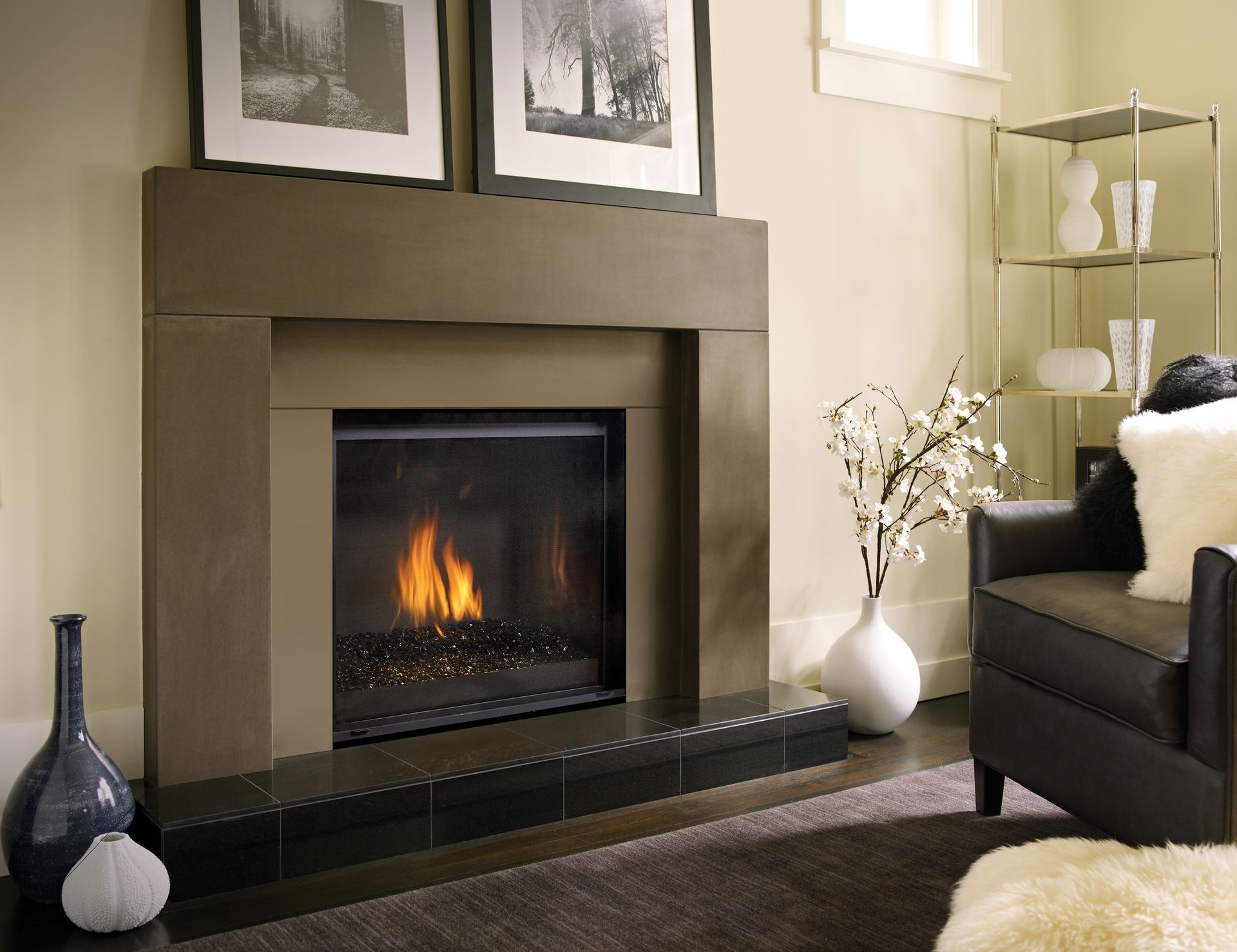Fireplace with flames, surrounded by a brown mantle. Two framed black-and-white photos hang above.