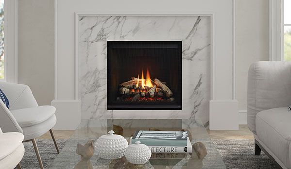 Fireplace with marble surround in a living room, flames burning in the hearth, and coffee table with decorative items in front.