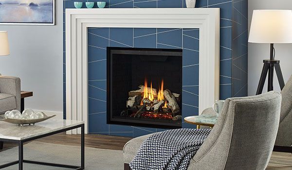 A modern fireplace with blue tile surround, white mantel, and a roaring fire. Living room setting with contemporary furniture.