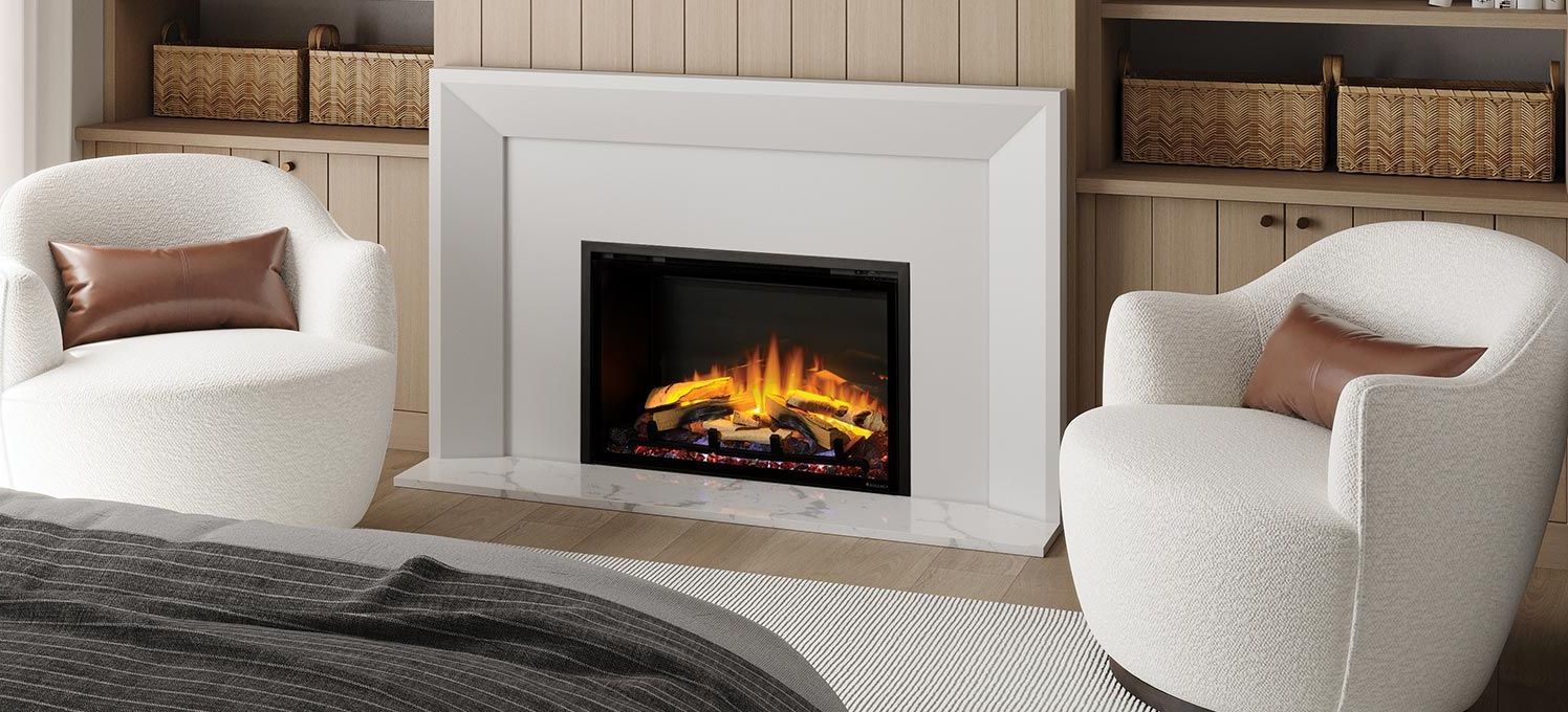 A cozy living space with a white fireplace, two white sherpa chairs, and a bed in the foreground.