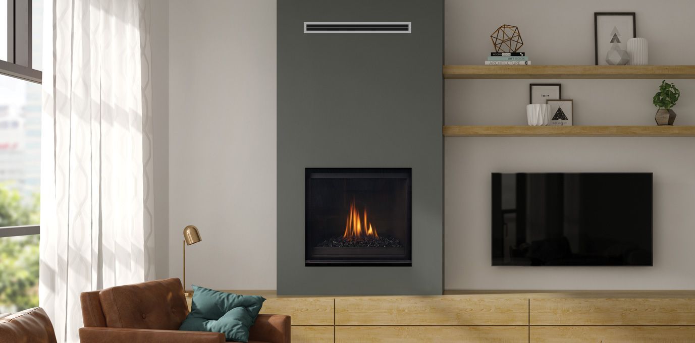 A modern living room with a gray fireplace, wooden shelves, a TV, and a brown sofa. The fireplace has a fire burning.