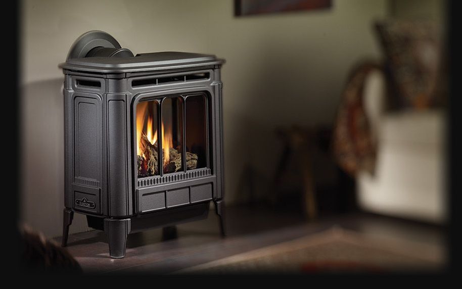 Black gas fireplace with flames in a living room setting, next to a couch.