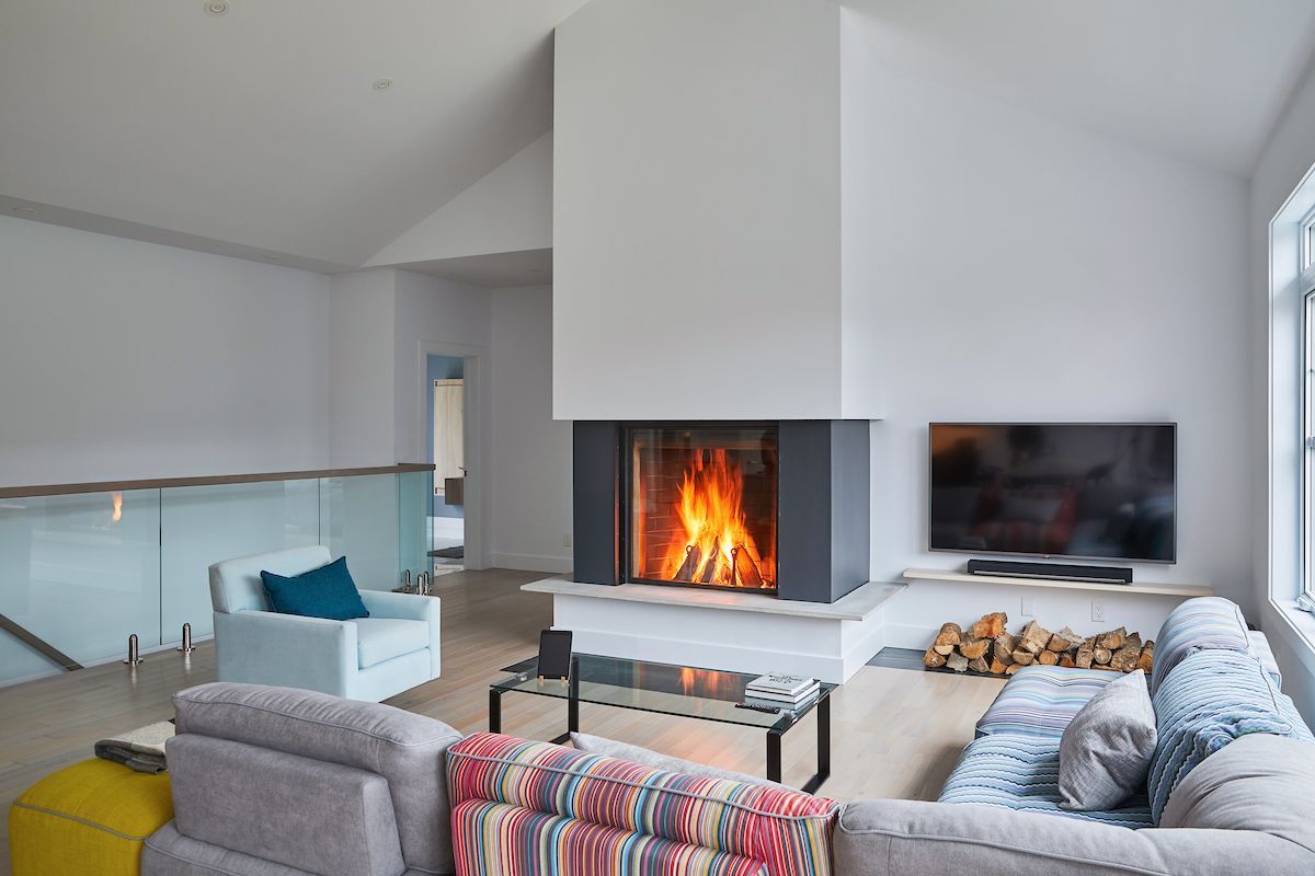 Cozy living room with a fireplace, TV, and sectional sofa; light wood floors and blue and gray accents.