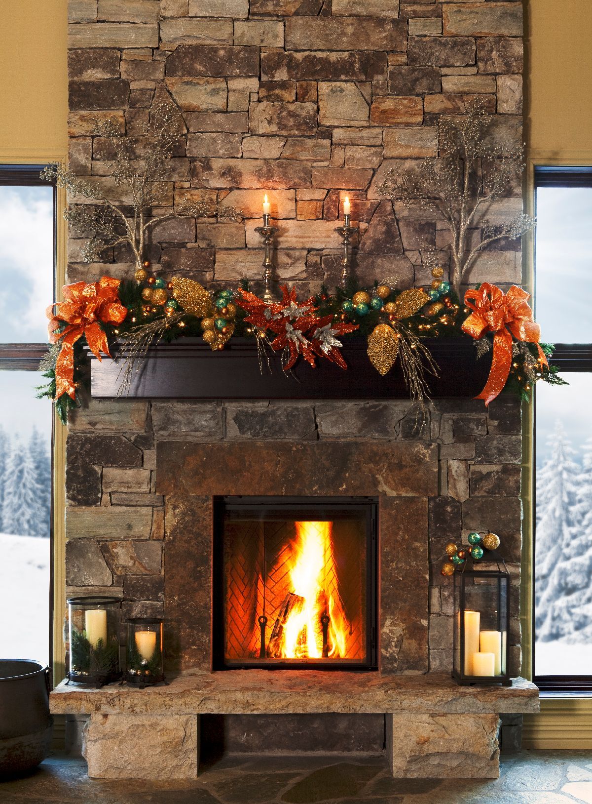 A fireplace with a stone facade and Christmas decorations, including lit candles, garland, and bows. The fire is burning.