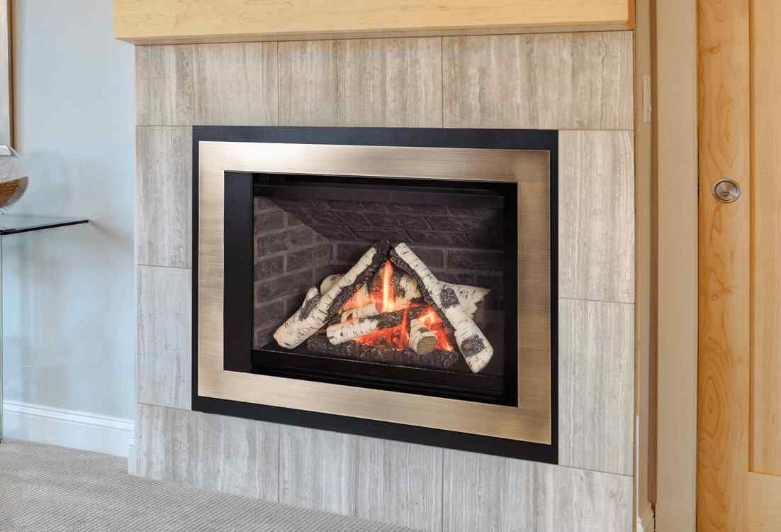 A gas fireplace with a glowing flame and faux logs, set within a silver and black frame, surrounded by tiled walls.